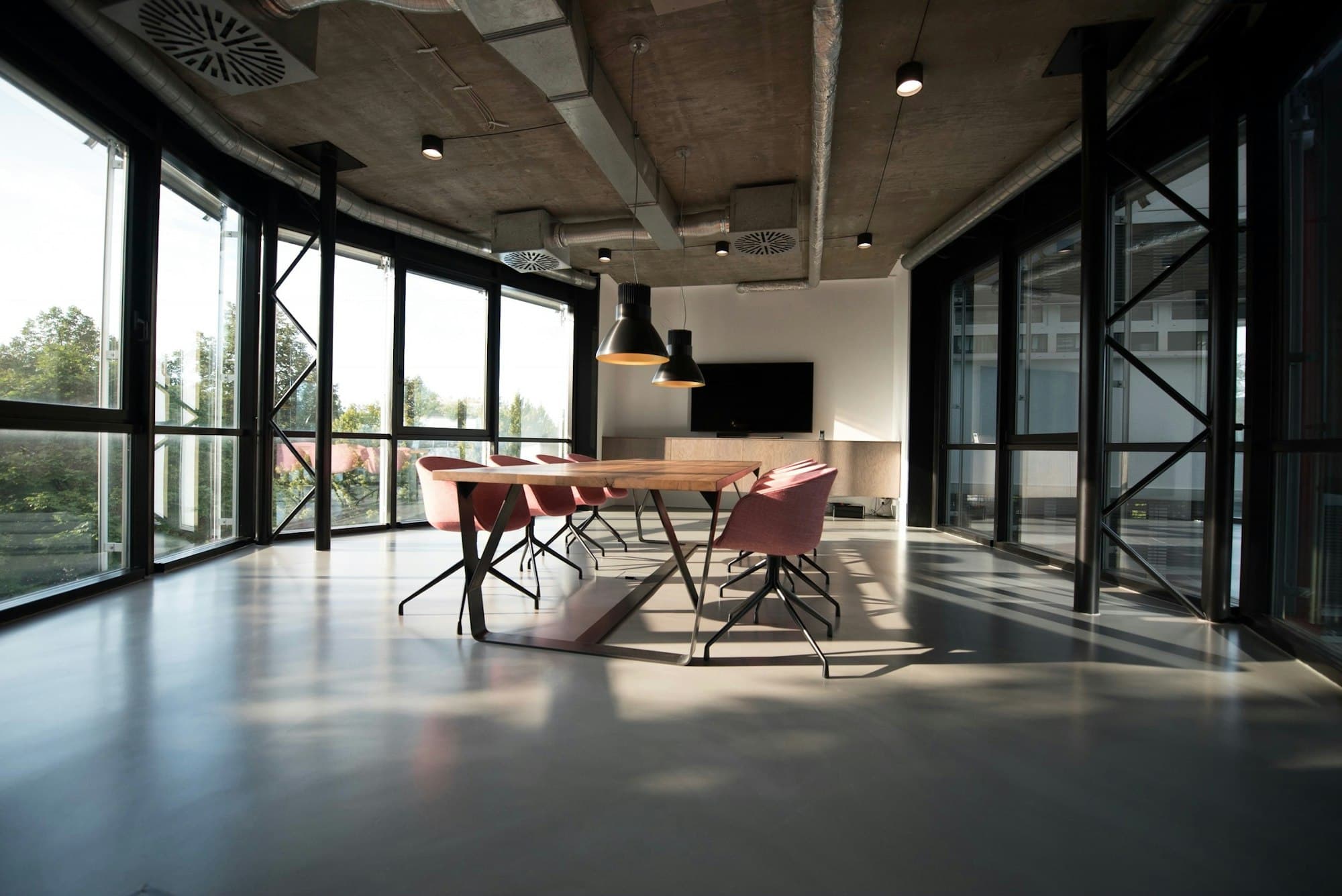 Bright industrial conference room with a long wooden table and floor-to-ceiling windows